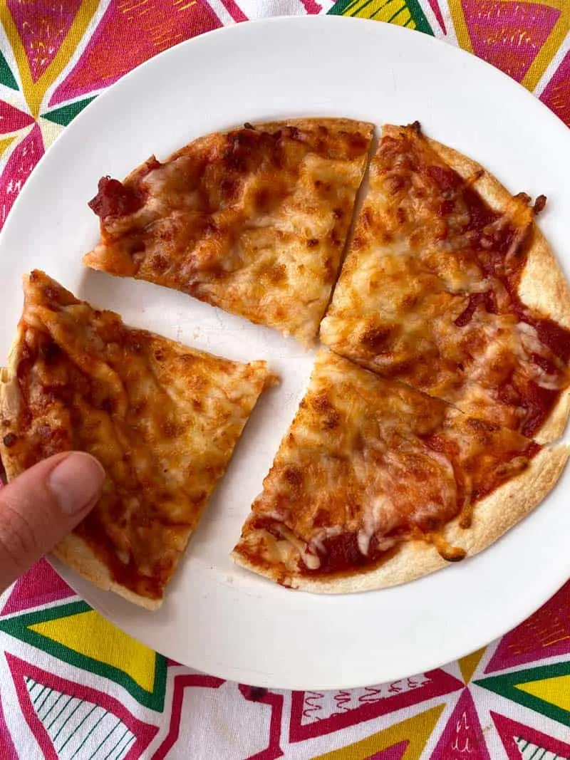 A person holding a slice of pizza on a plate.