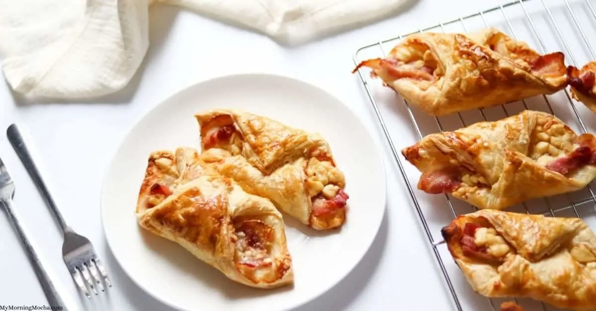 Three bacon and cheese turnover on a cooling rack next to two that are in a white plate.