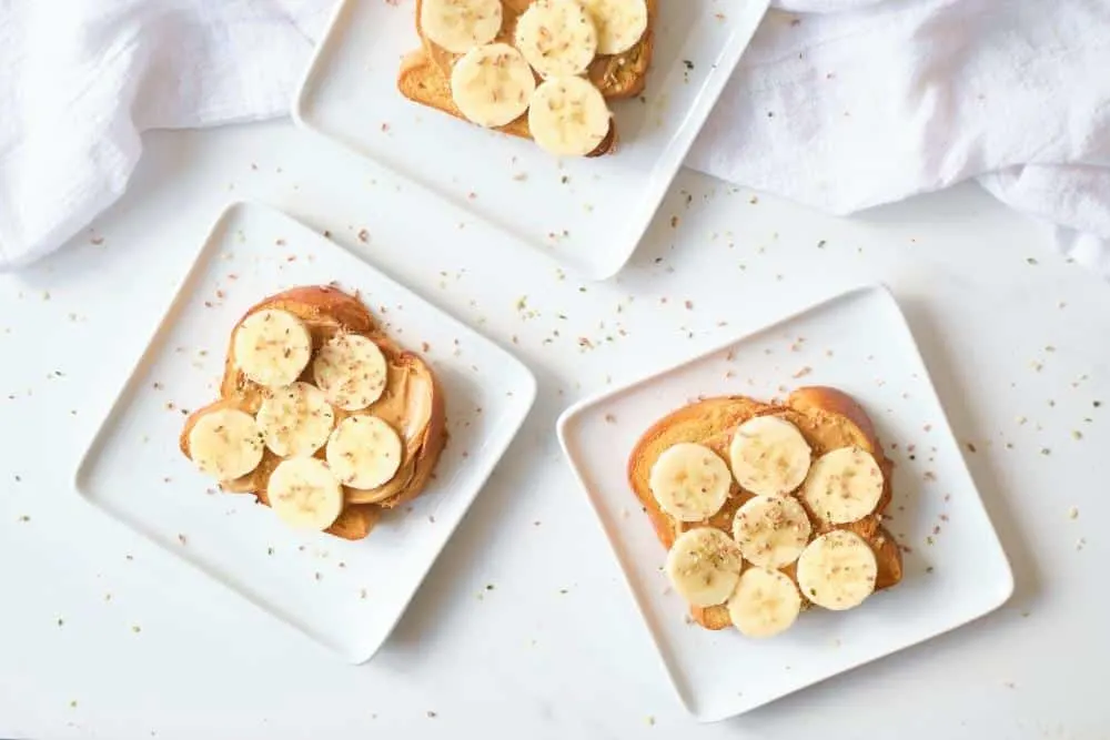 Three plates of toast with peanut butter and sliced bananas.