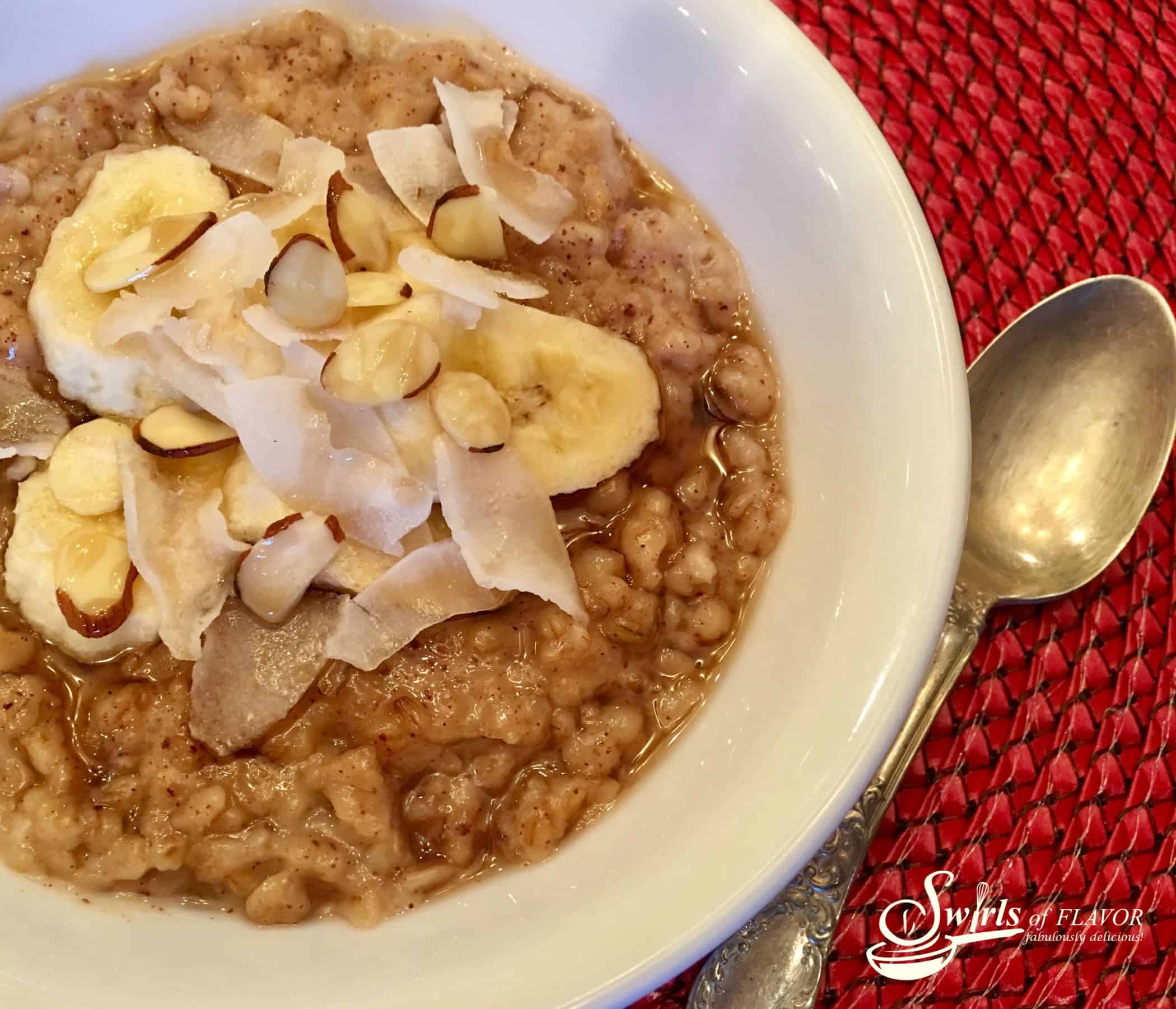 A bowl of banana coconut oatmeal next to a spoon.