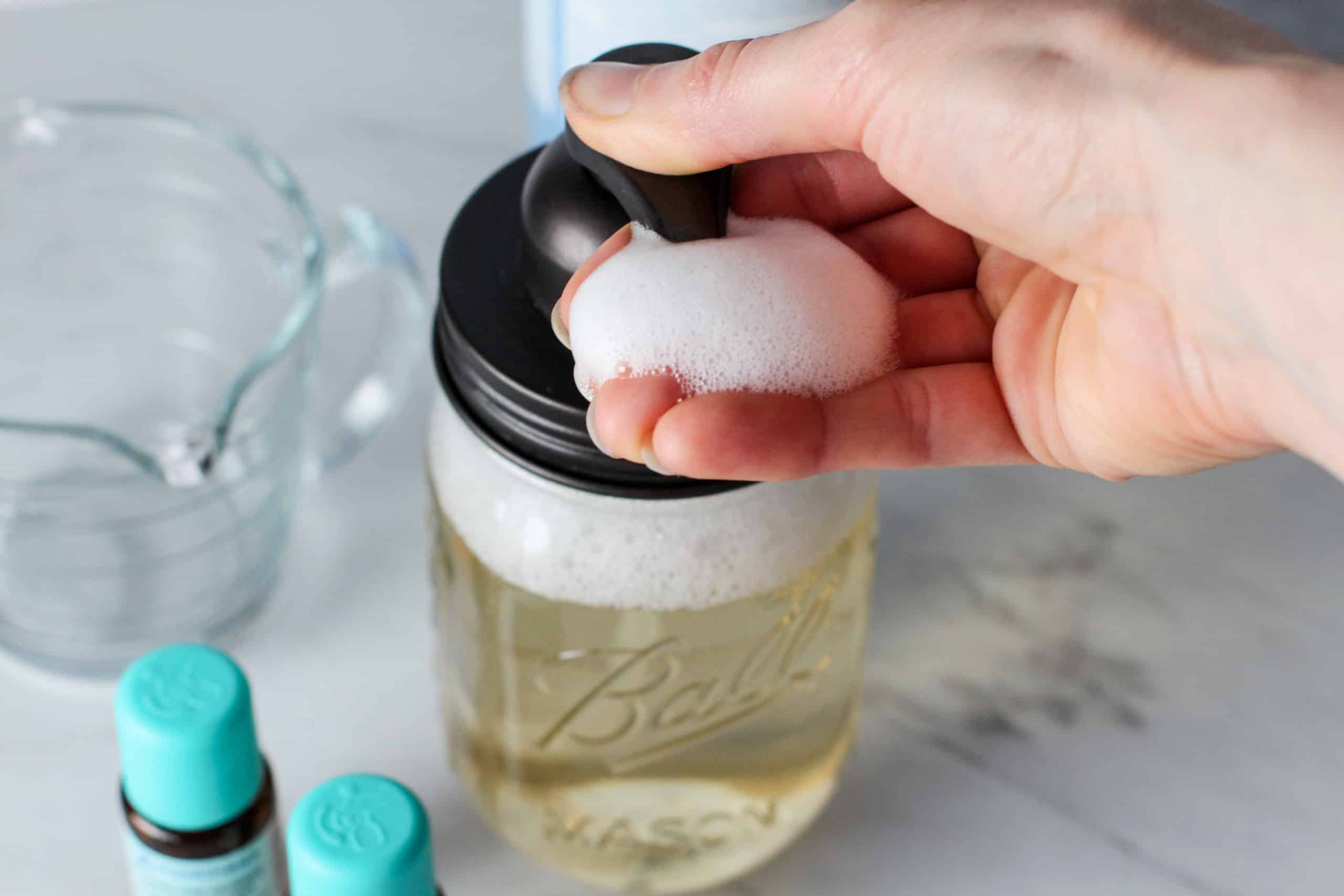 A person getting a pump of homemade foaming soap.