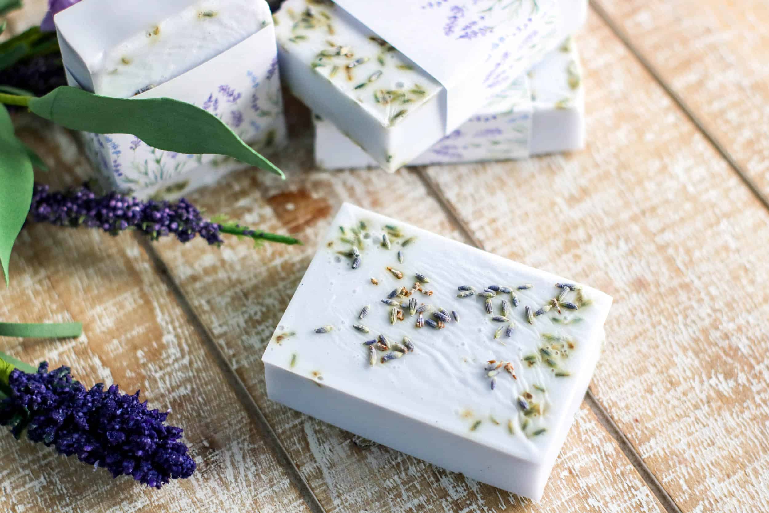 Lavender soap bars next to lavender flowers and green leaves.