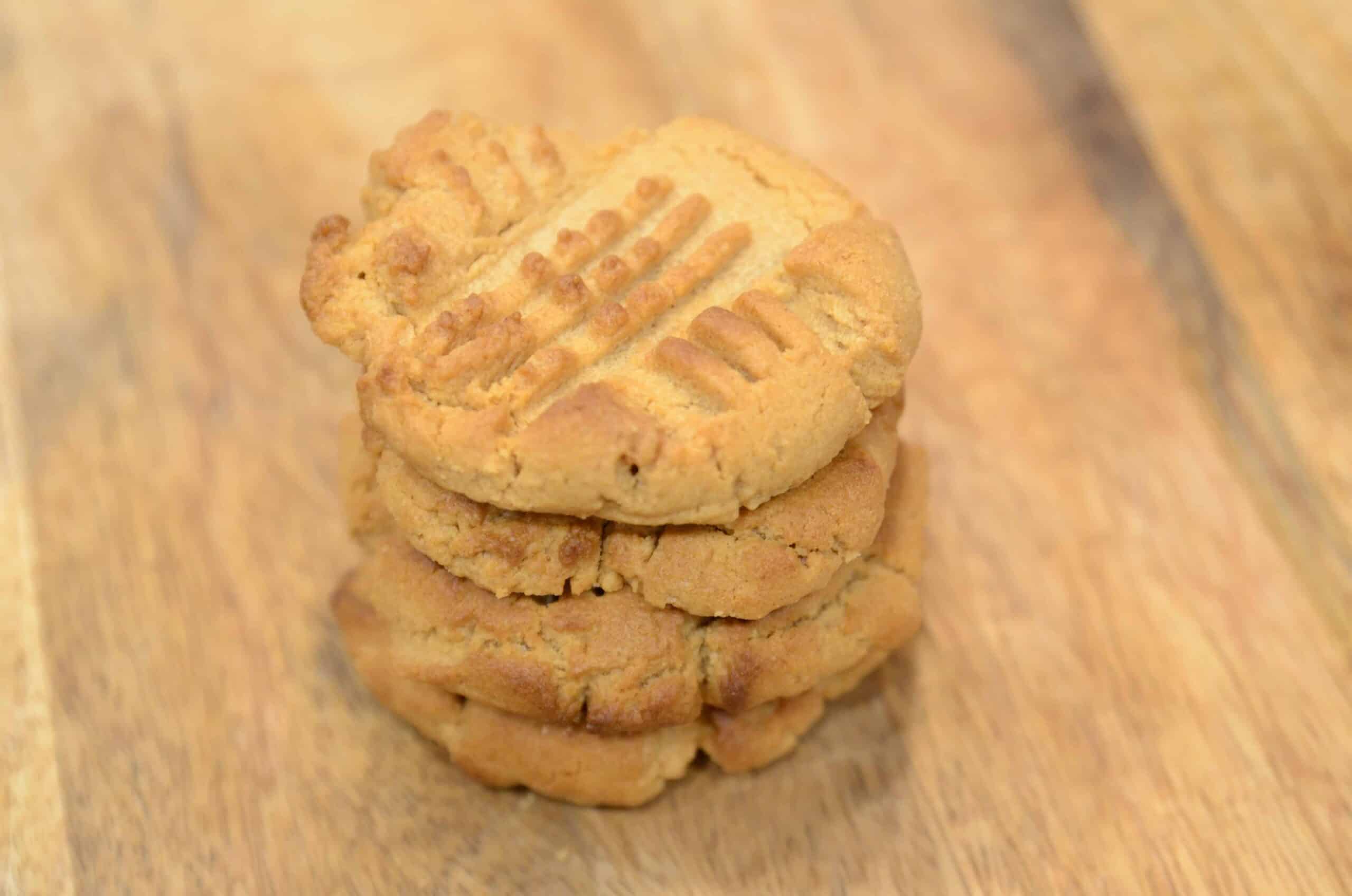 A stack of 3-ingredient keto peanut butter cookies on a wooden counter background.
