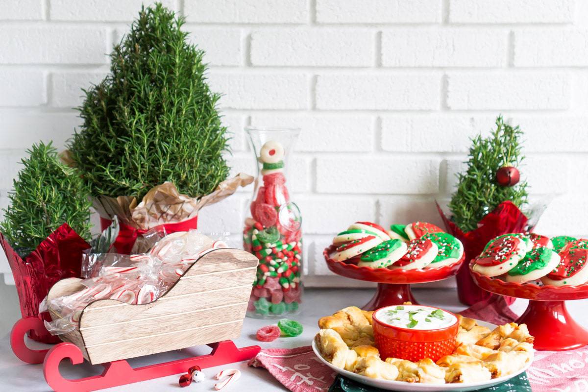 An appetizer tray with red and green cookies, and candy canes in a sleigh.