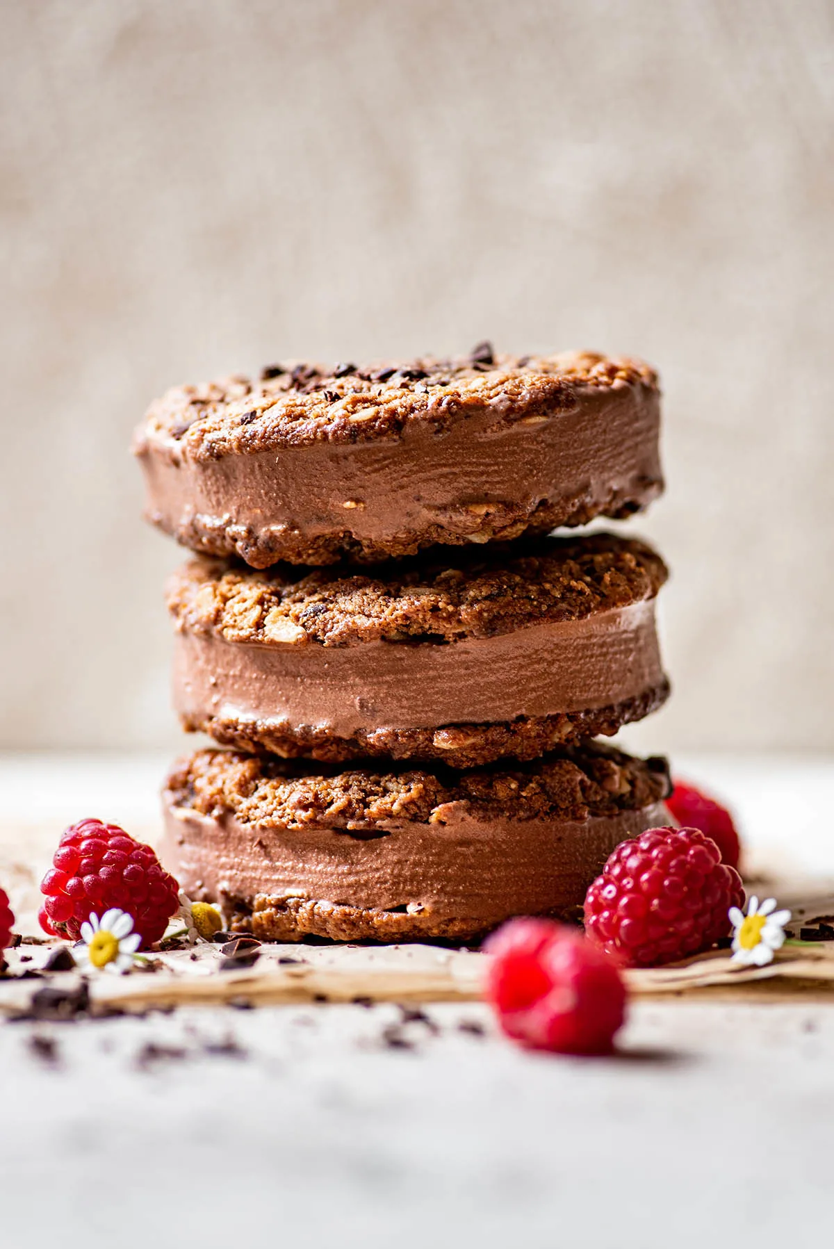 A stack of three chocolate coconut milk ice cream sandwiches with berries on the side.