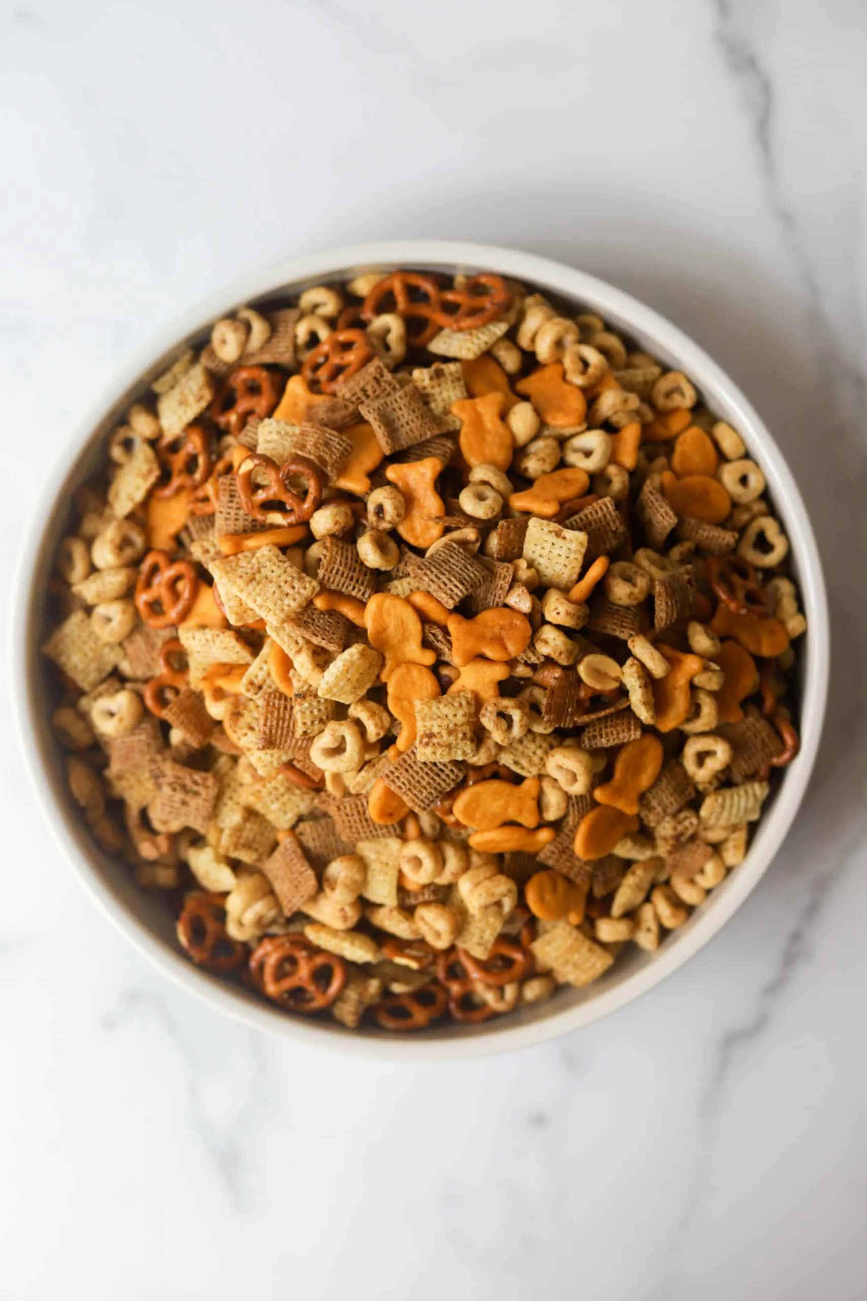 Healthy chex mix party snack with nuts in a white bowl.