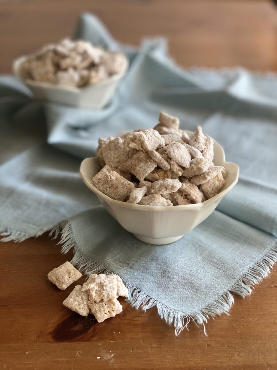 Two muddy buddies snack in white bowls on a blue cloth.