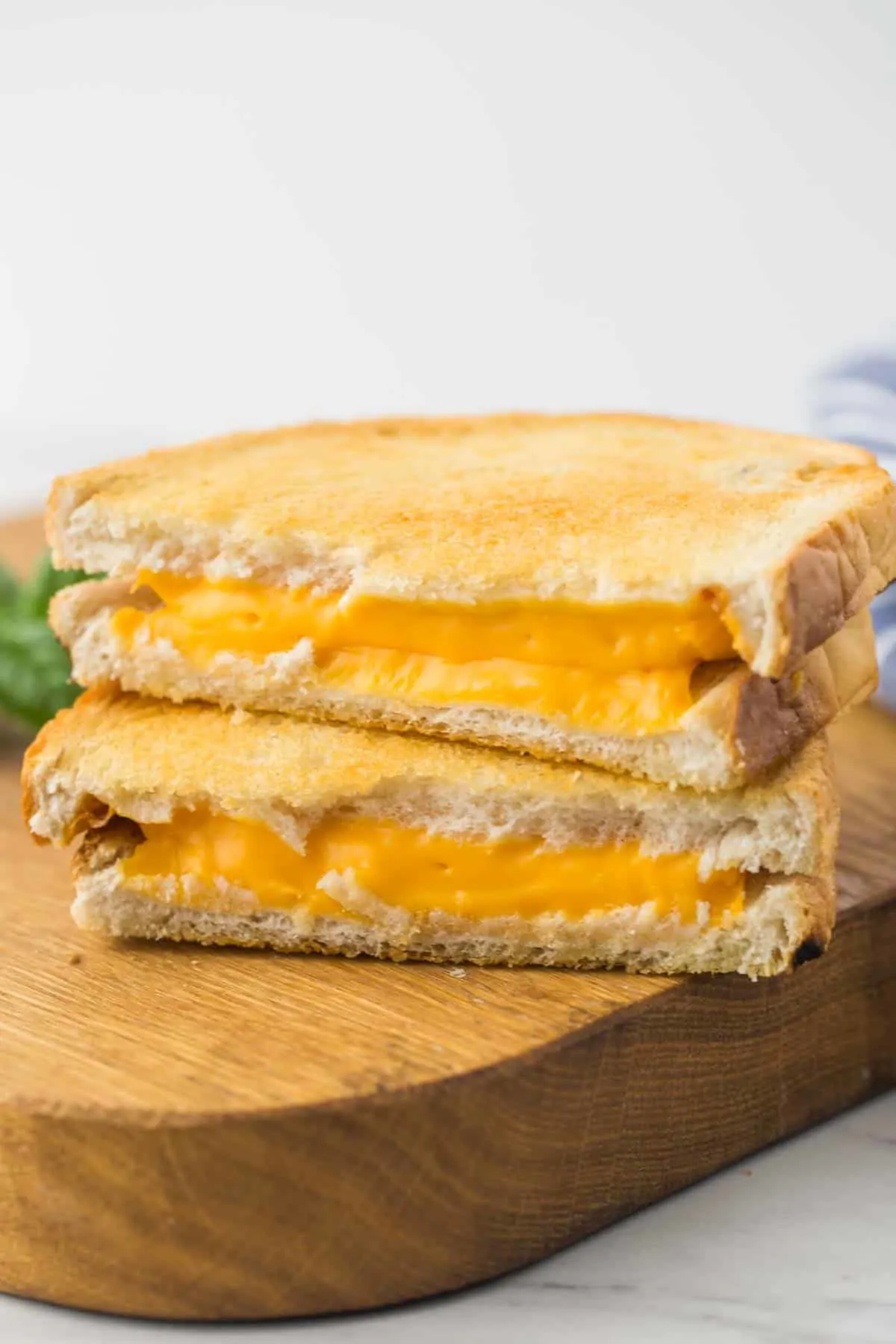 Two air fried grilled cheese stacked together on a cutting board.