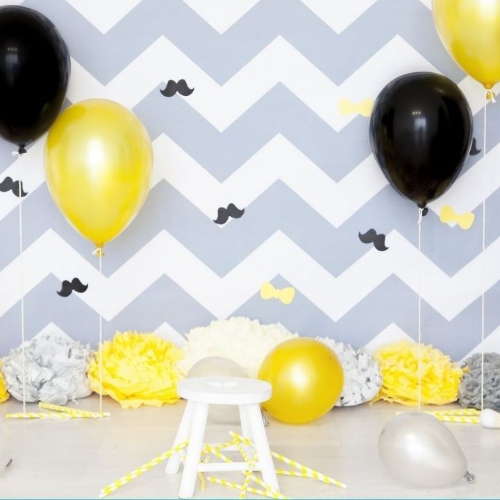 Birthday party decoration with black, grey and yellow balloons.