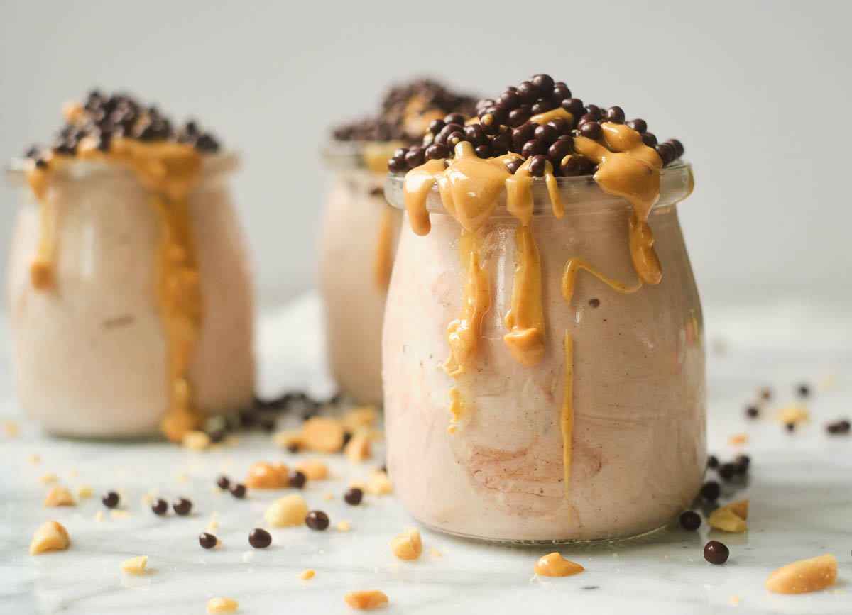 Three glasses of peanut butter yogurt with caramel drizzle and chocolate chip topping.