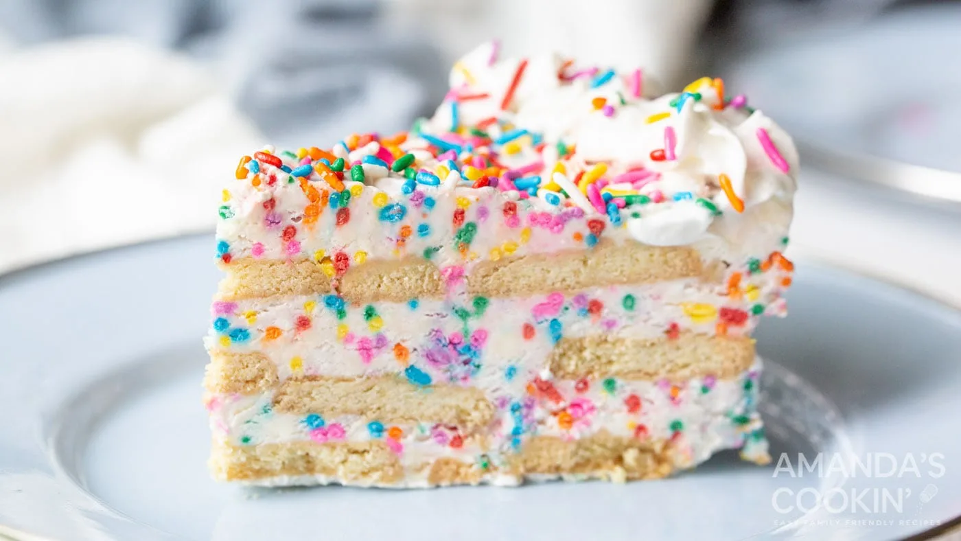 Close up of a slice of funfetti cake with sprinkles on a white plate.