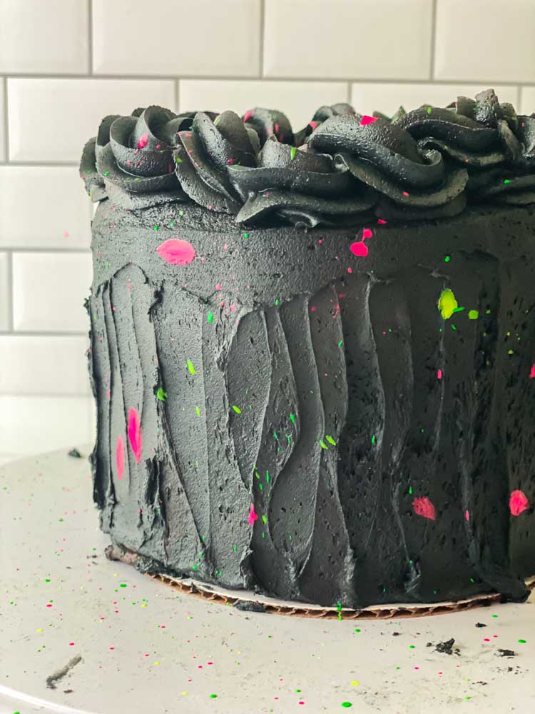 Glow in the dark party cake with black frosting and a splash of neon green and pink.