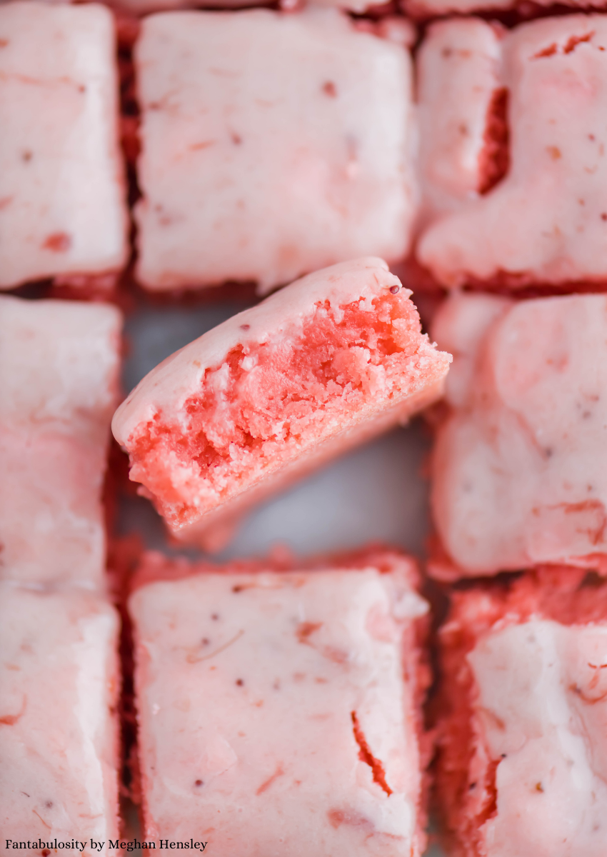 A close up photo of strawberry brownies cut in squares with one turned upright.