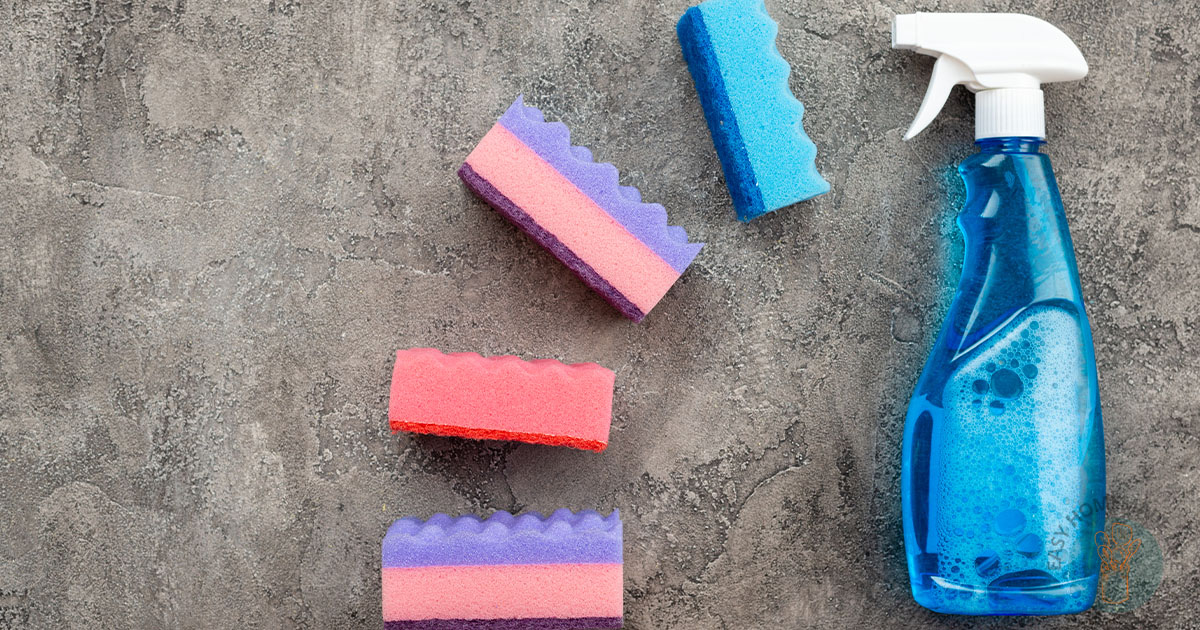 A blue spray bottle next to four sponges in different color.