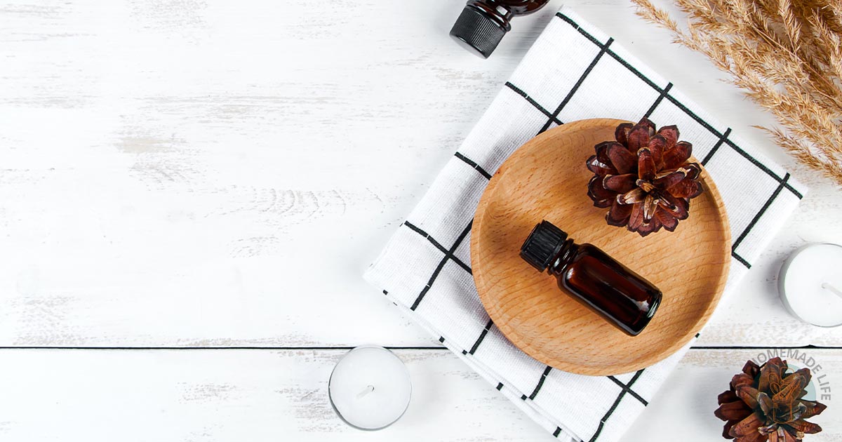 A wooden plate with pine cones and a bottle of woodsy essential oil blend.