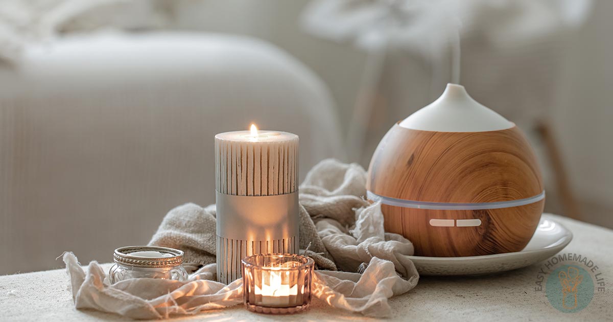 Essential oil diffuser diffusing mist next to a small lit candle in a jar.