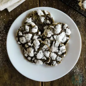 Crinkle cookies on a white plate with powdered sugar.