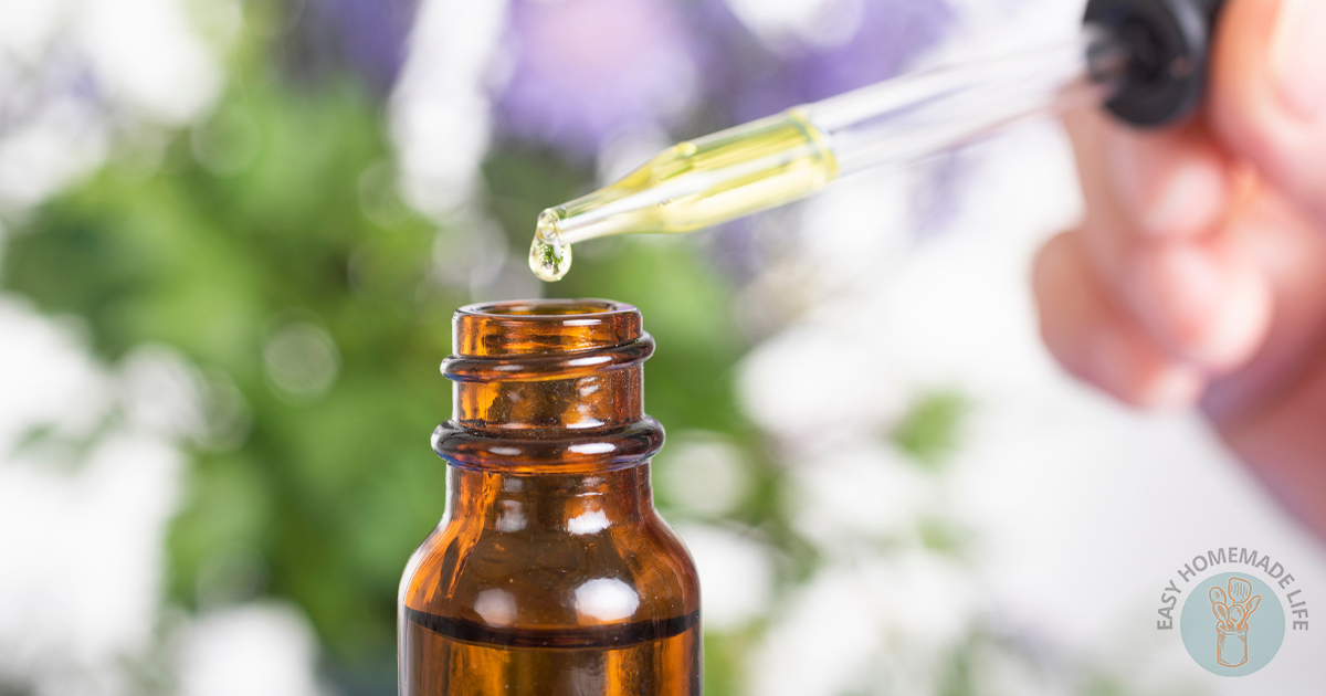 A glass dropper directed to the mouth of the bottle with the essential oil coming out of it.