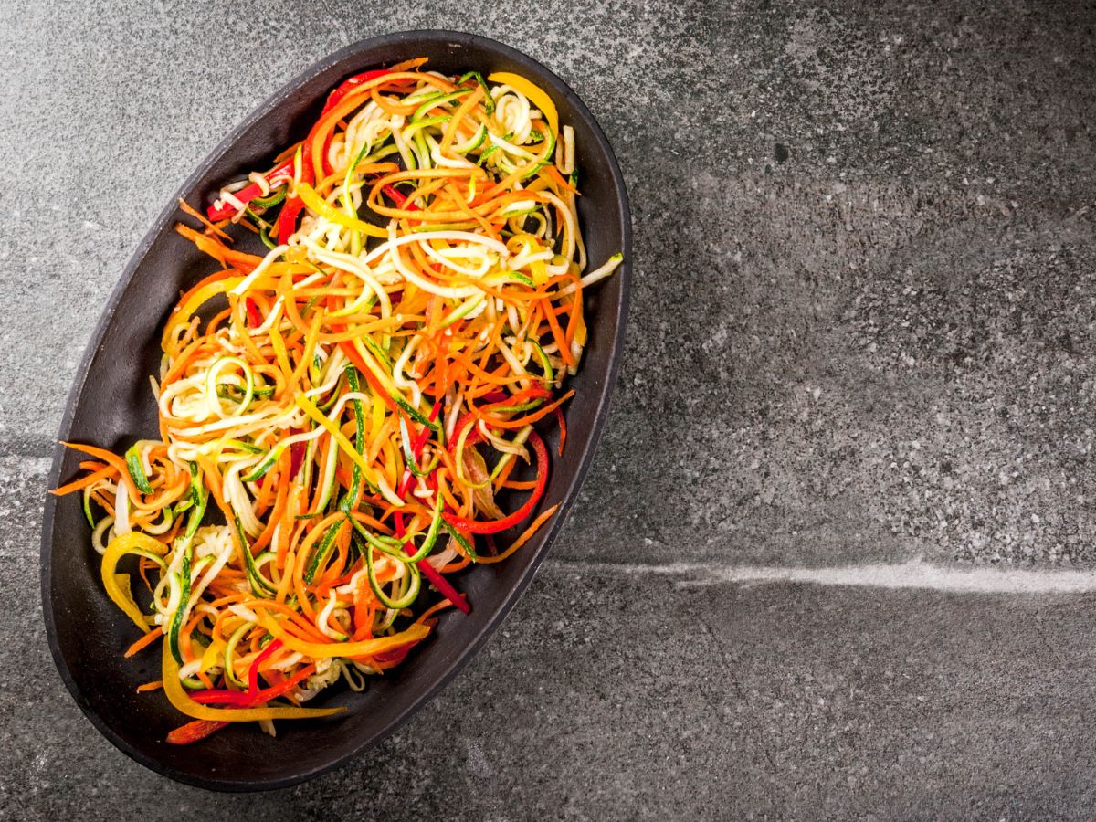 Different color veggie noodles on a black platter.