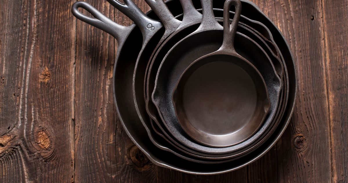 A clean cast iron skillet with green checkered kitchen towel and herbs.