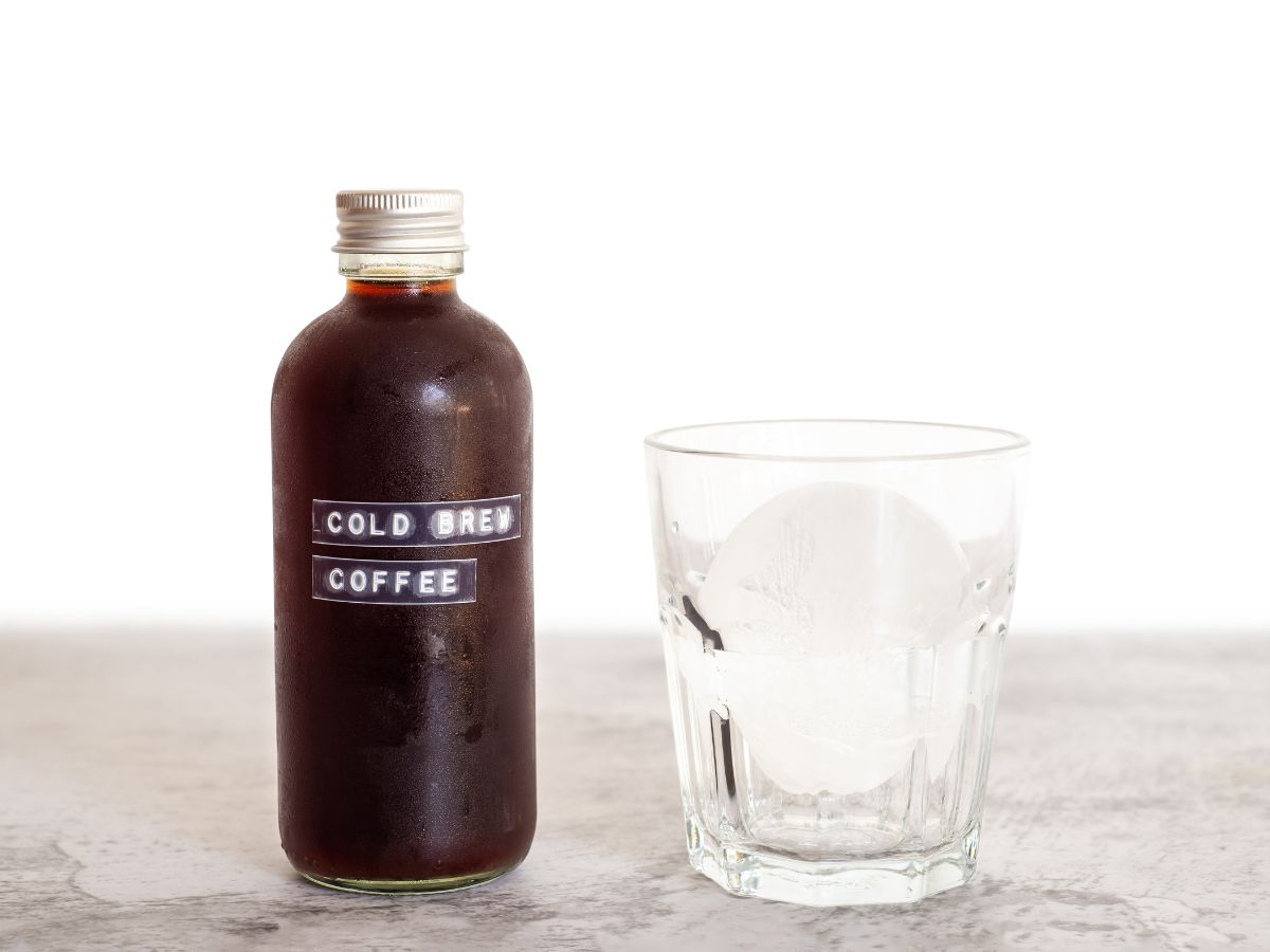 Jar of cold brew concentrate and empty glass with ice, ready to serve.