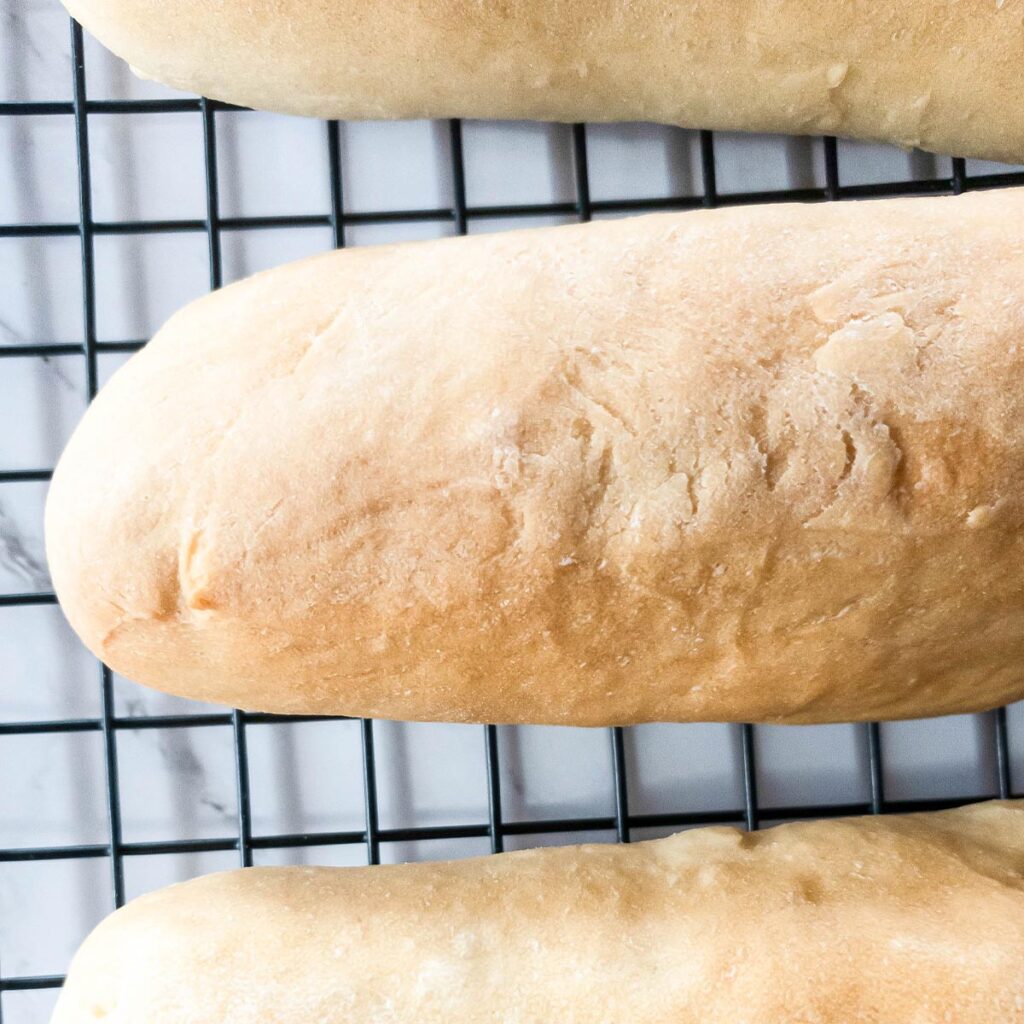 Three loaves of bread on a cooling rack.