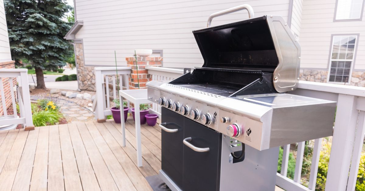 A bbq grill on a backyard deck outside.