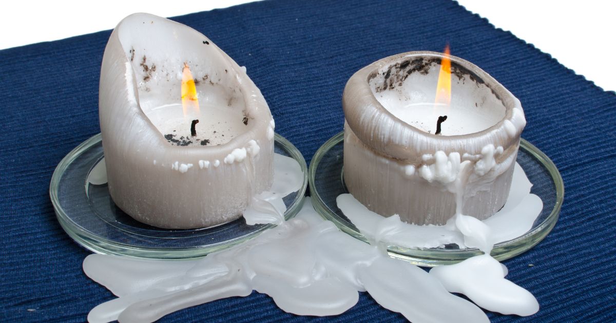 White candles melting on blue cloth.