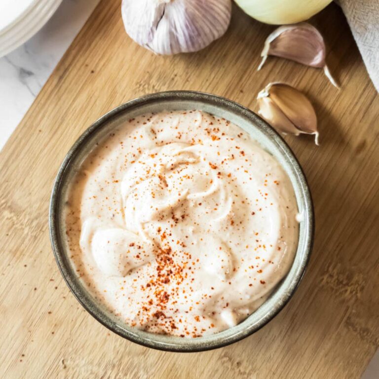 A bowl of Popeye's spicy mayonnaise on a cutting board.