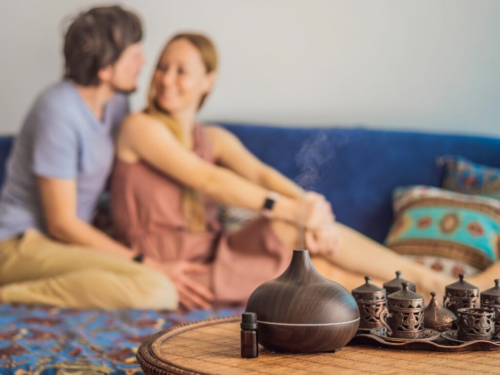 A couple sitting on a couch with an aromatherapy diffuser.