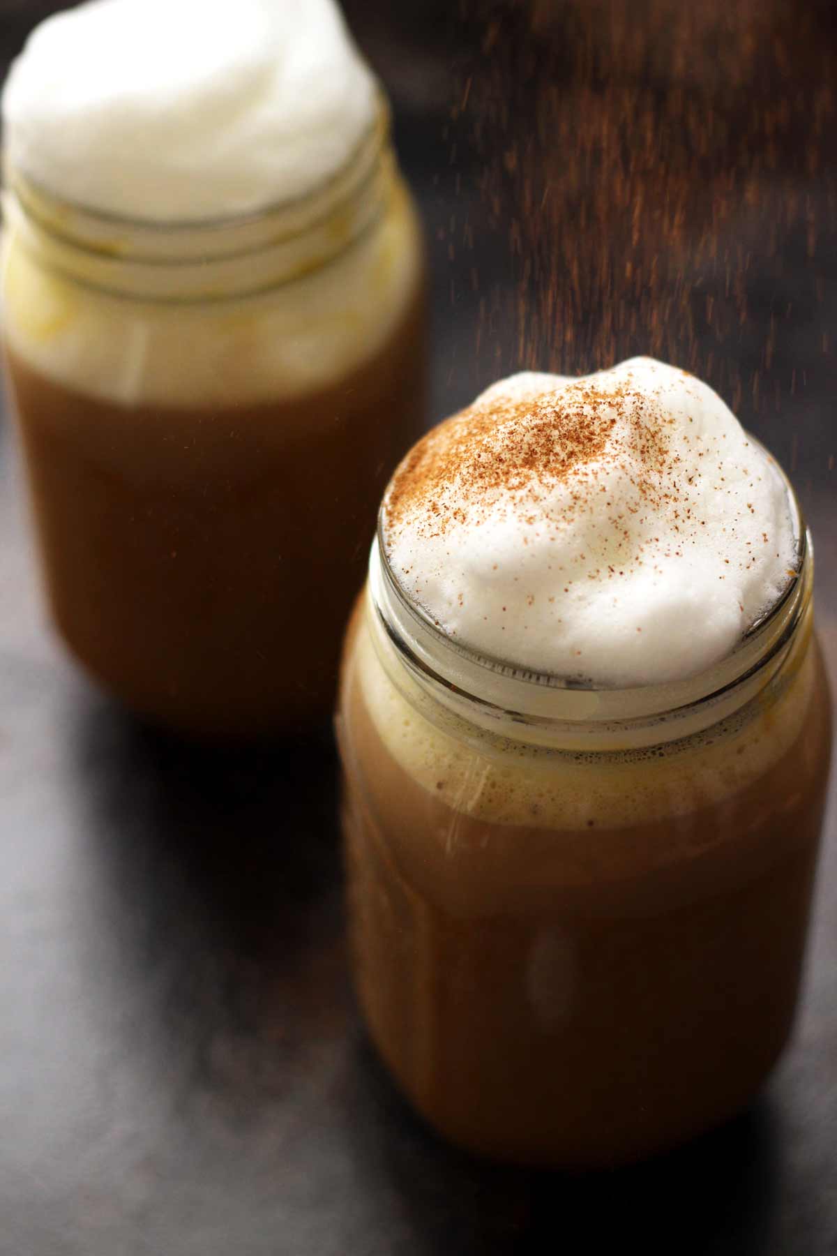 Two jars of coffee with whipped cream and cinnamon.