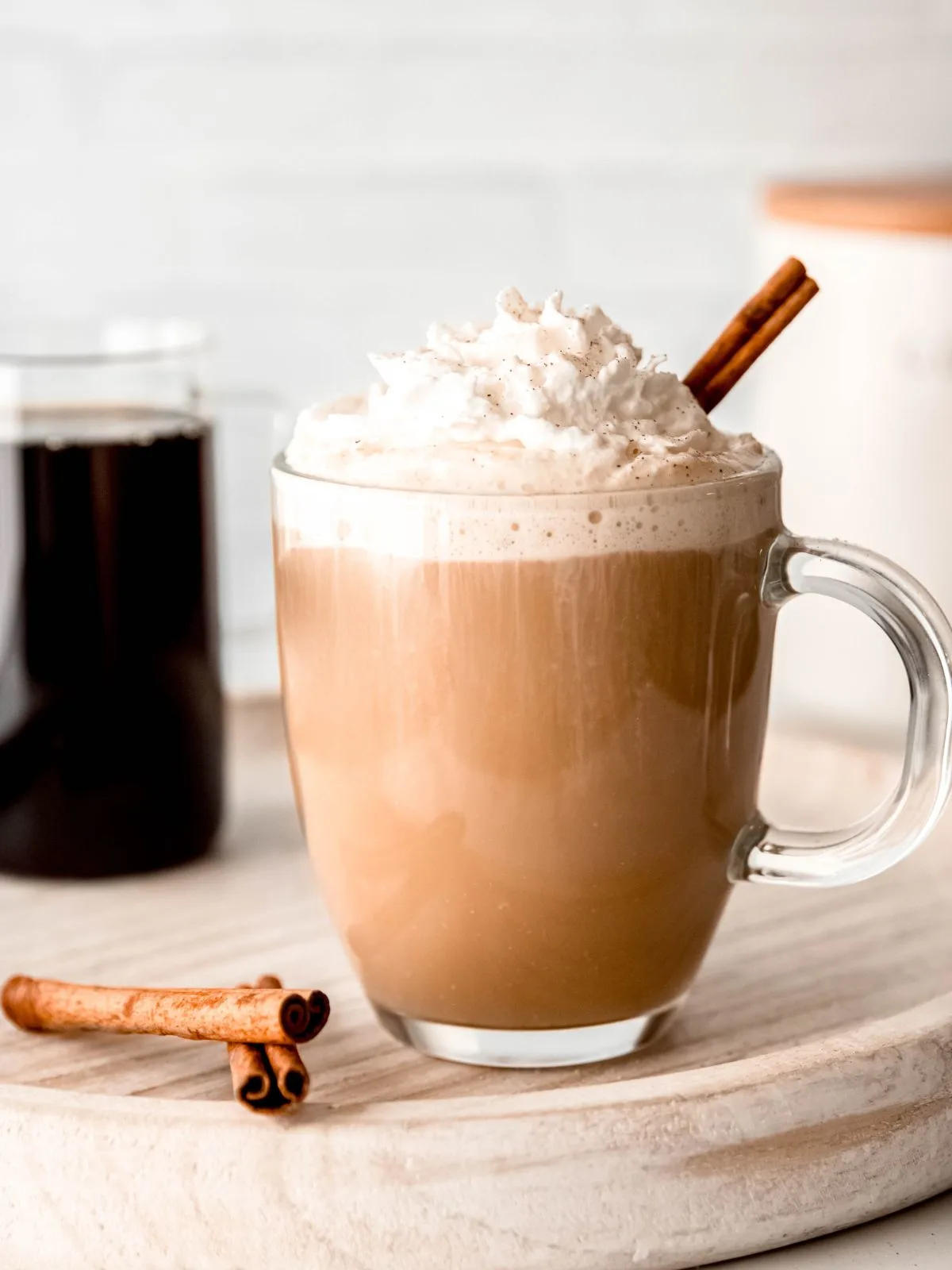A cup of coffee with whipped cream and cinnamon sticks.