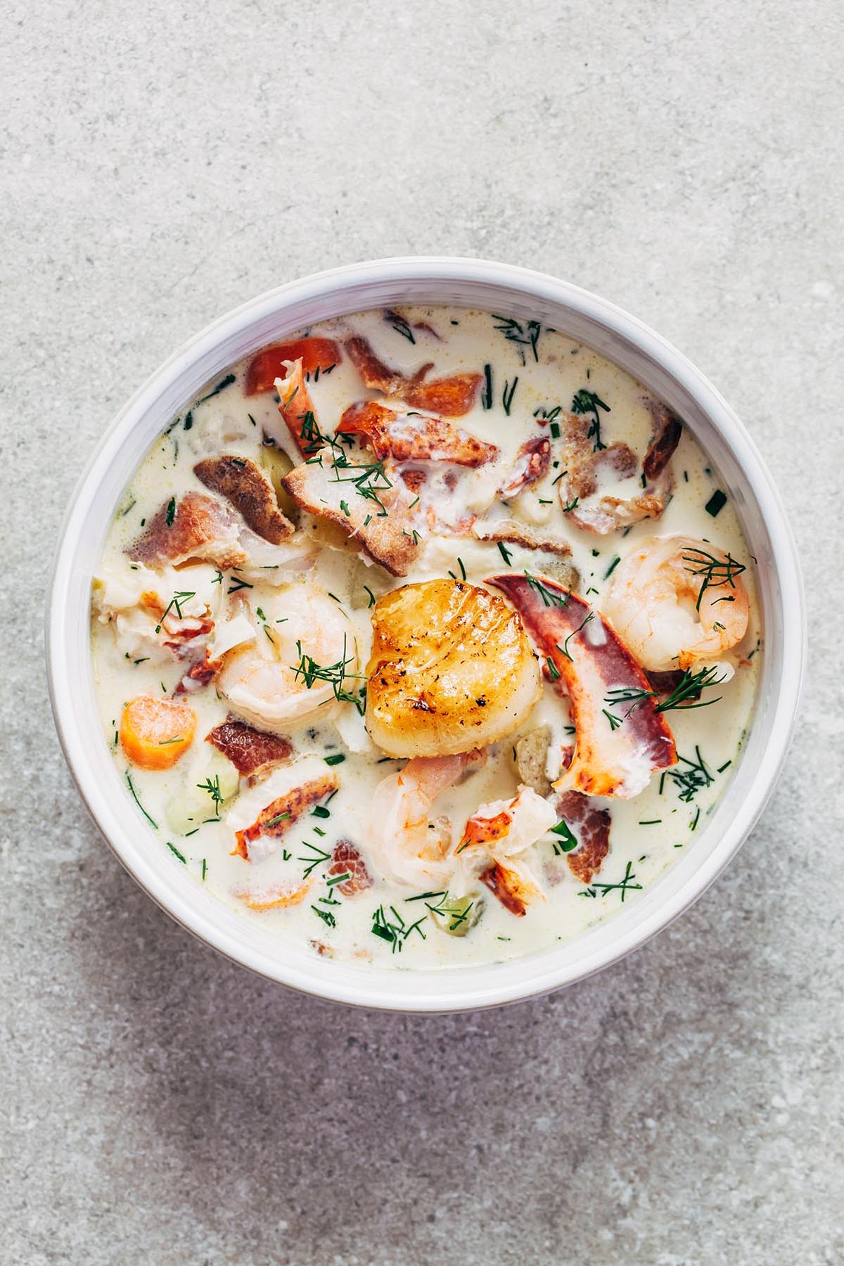 A bowl of seafood chowder with shrimp and dill.