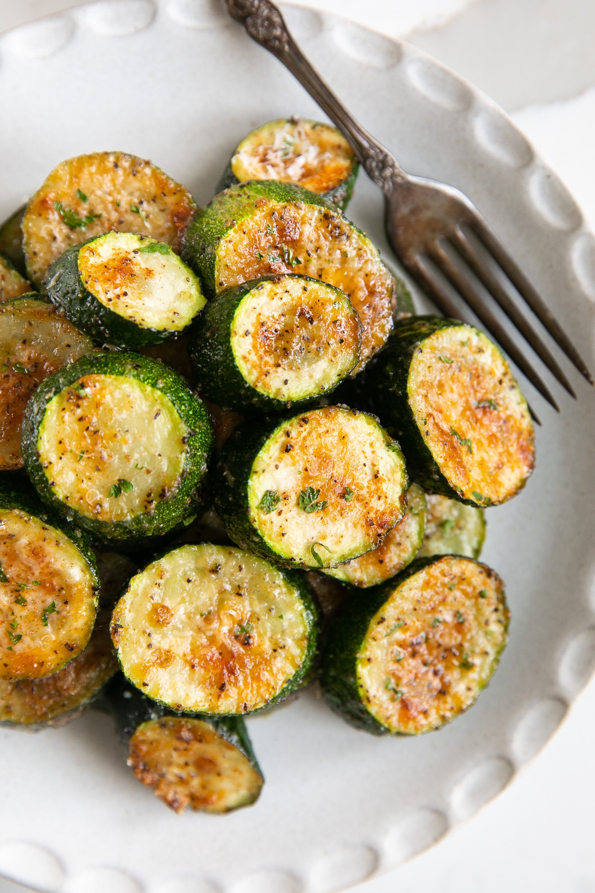 Grilled zucchini on a white plate with a fork.
