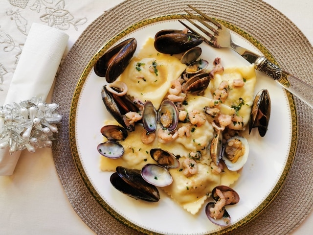 Pasta with clams and mussels on a white plate with fork next to a white napkin.