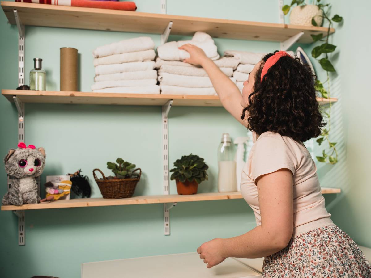 A woman is organizing towels in her laundry room, applying decluttering tips.