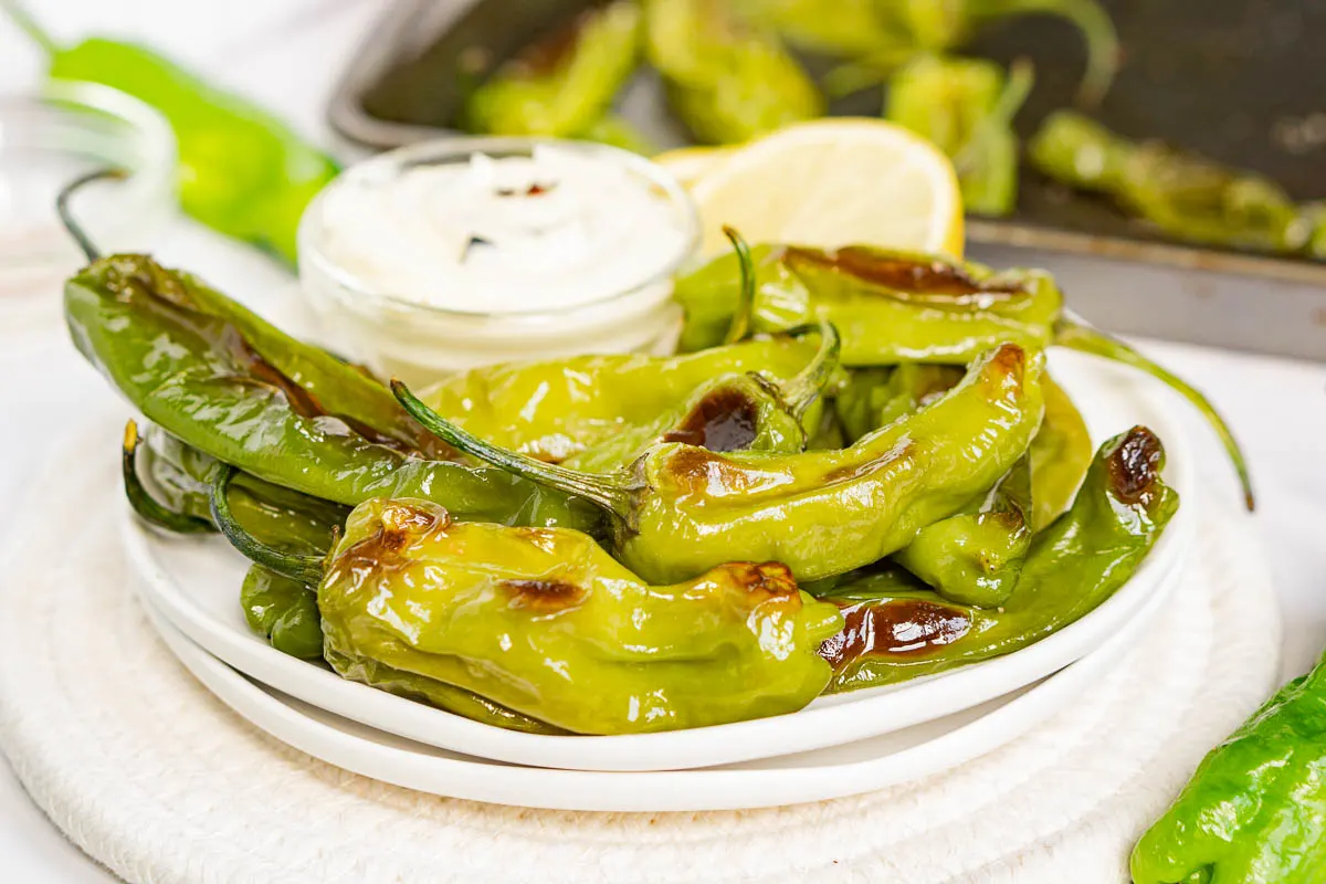 Green peppers on a plate with dipping sauce.