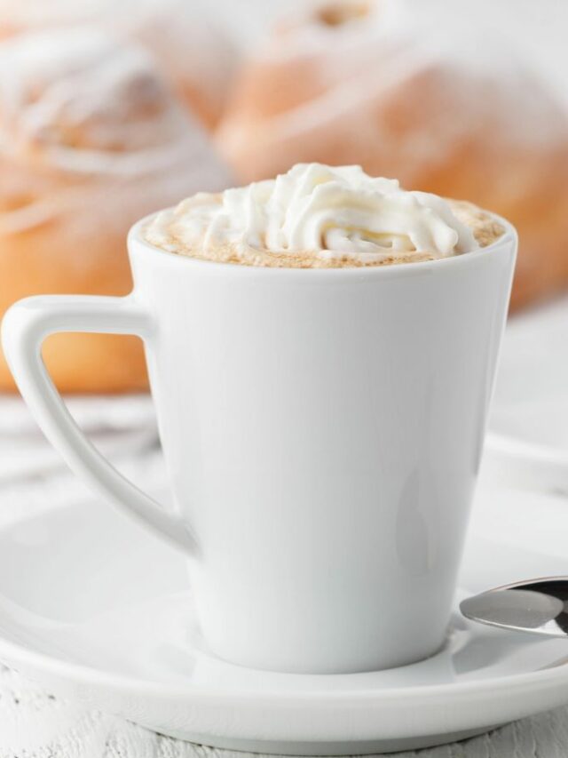 A white cup of coffee with whipped cream on top.