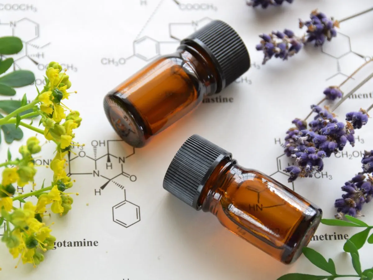 Bottles of essential oil next to flowers.