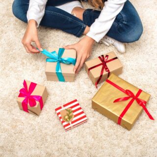 A teen girl is sitting on the floor with a gifts in front of her.