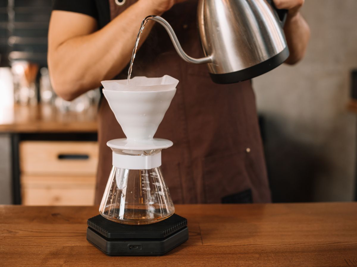 A man pouring water into a coffee maker filter.