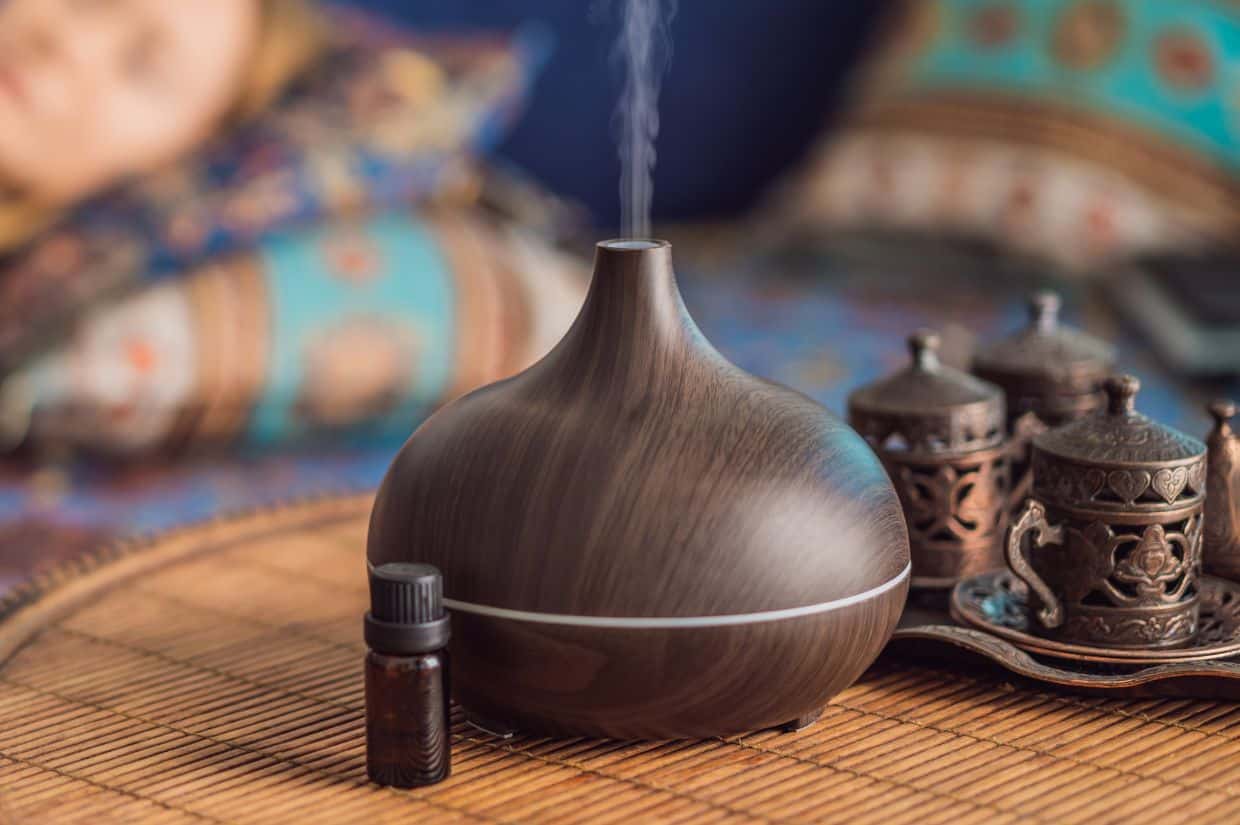 An essential oil diffuser next to a bed.