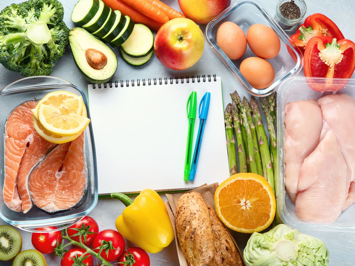 A notepad with a note about healthy eating is surrounded by a variety of foods.