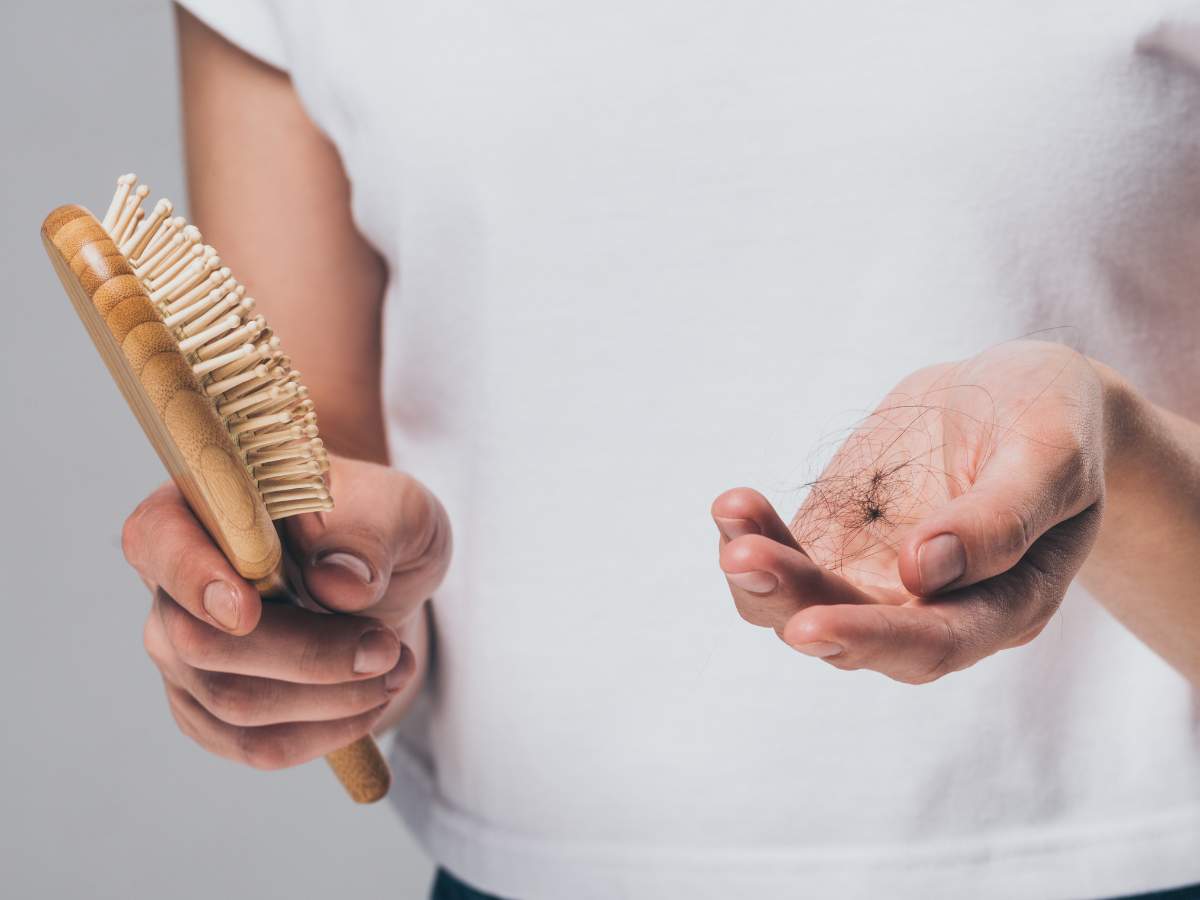 A woman holding a brush and a strand of hair.