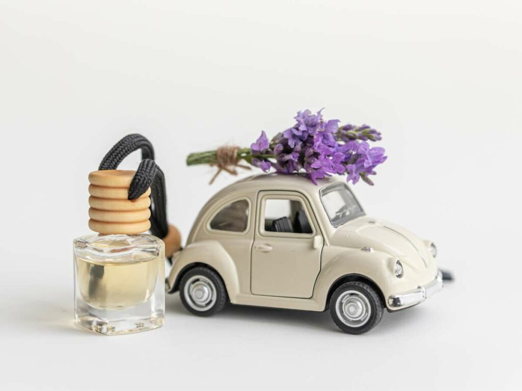 A miniature beige car with purple flowers on top.