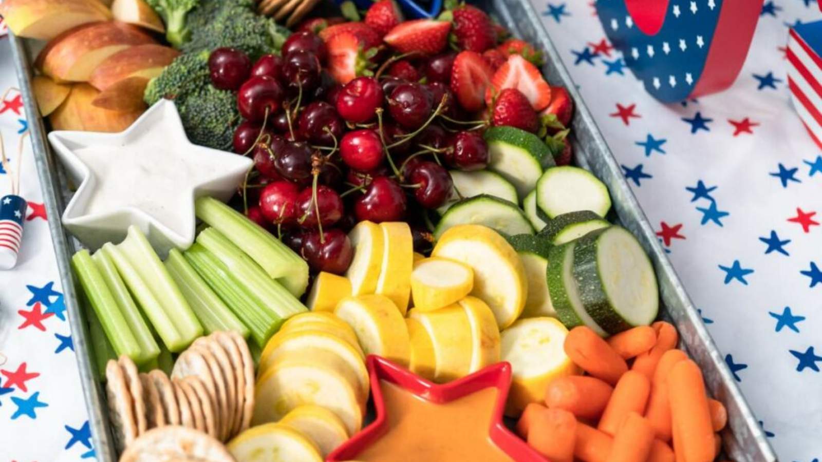 A tray of assorted fruits, vegetables, and crackers on a table with USA letters in the background.