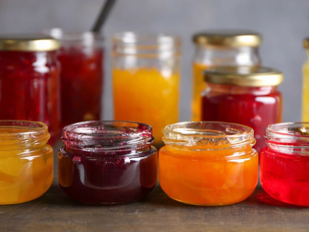 Several open and closed jars of assorted jams and preserve.