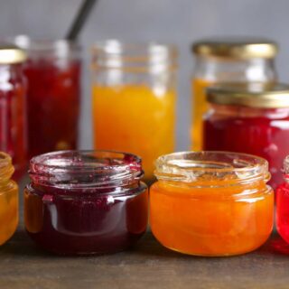Several open and closed jars of assorted jams and preserve.