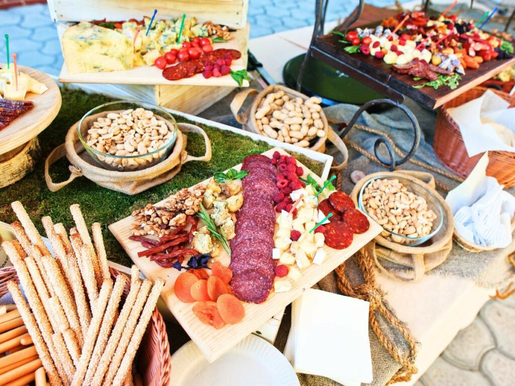 A diverse charcuterie spread featuring meats, cheeses, nuts, dried fruits, breadsticks, and assorted.