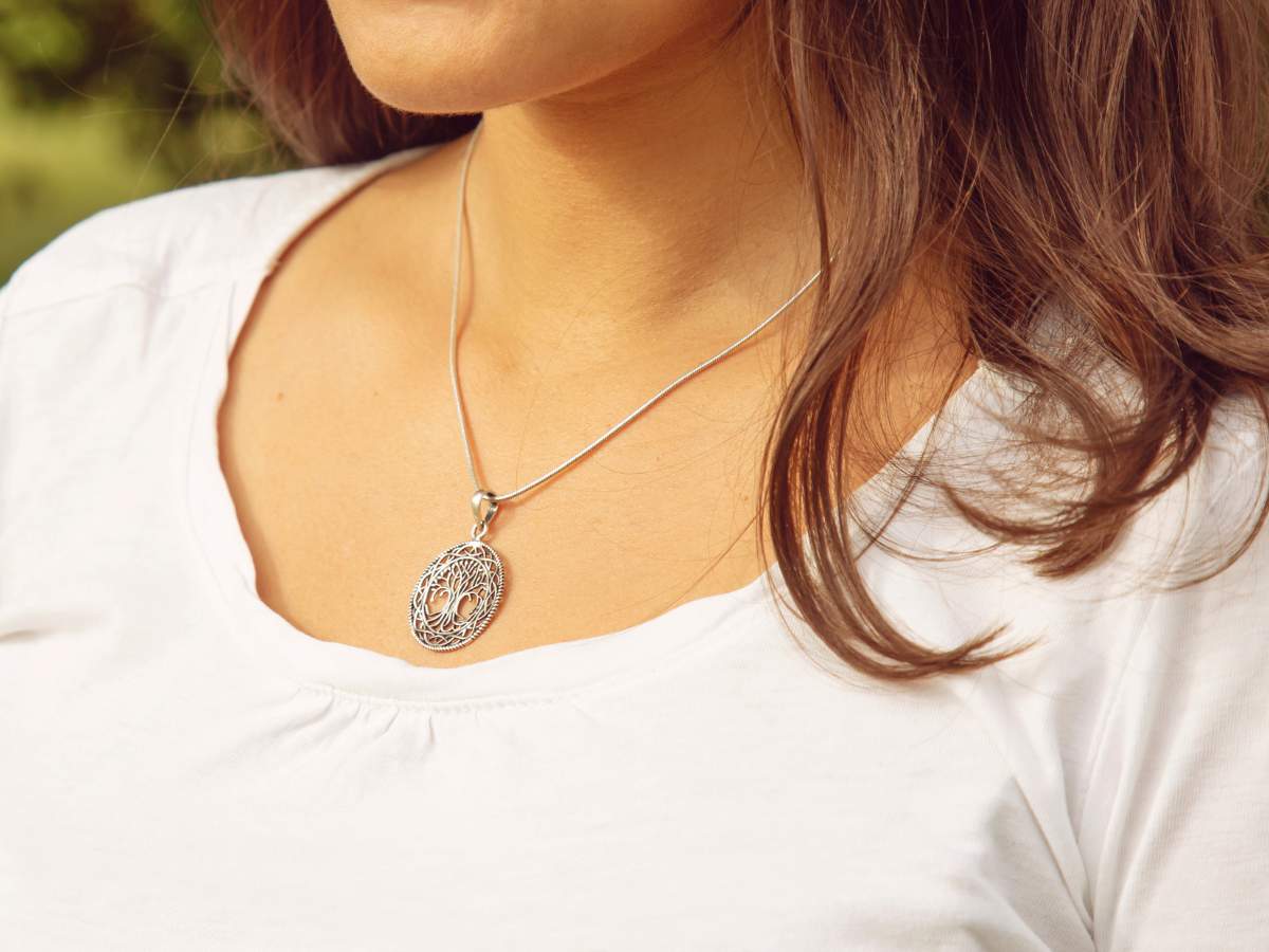 A person wearing a white shirt and a silver pendant necklace.